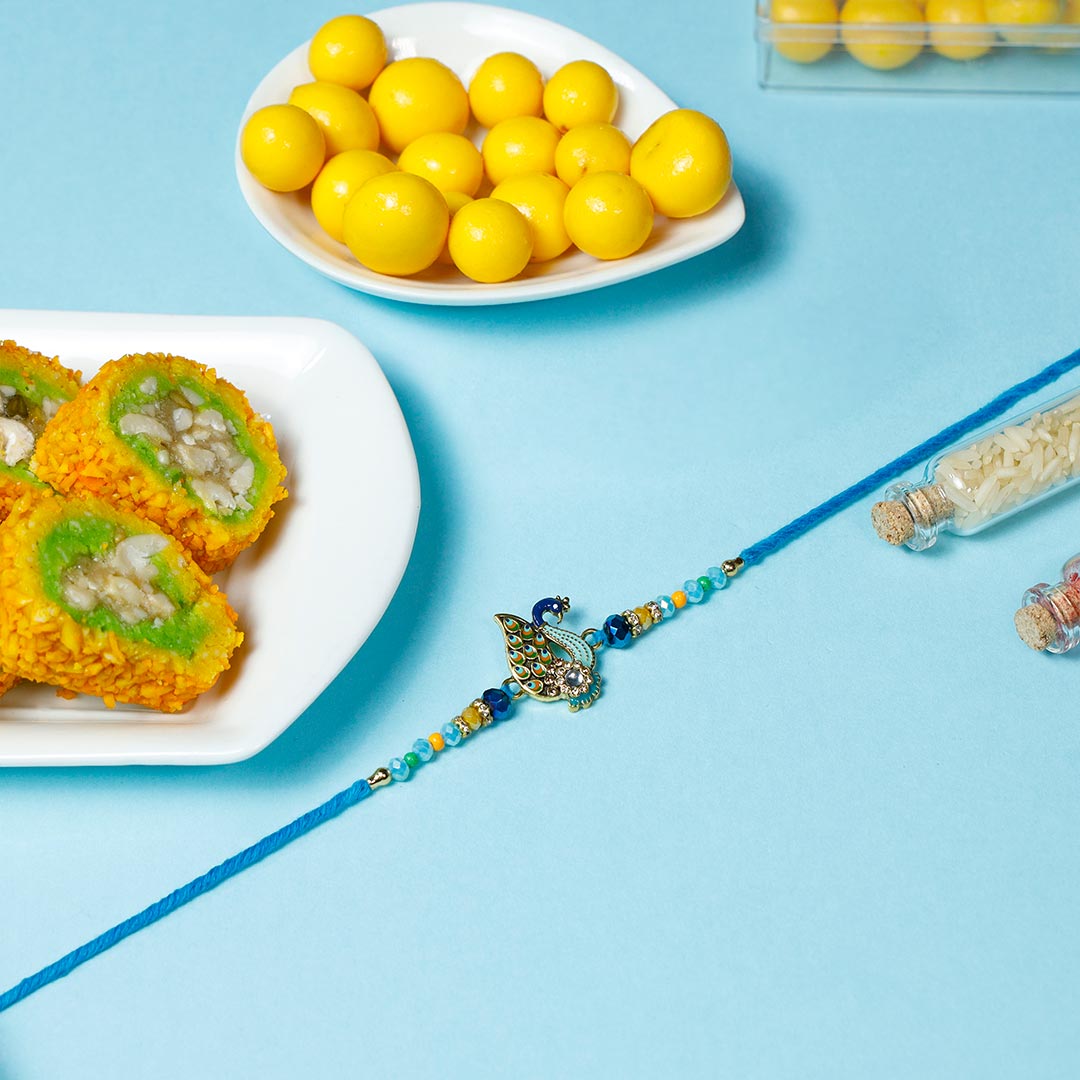 Beautiful Peacock Rakhi with Pista Barfi & Dragees Order Now