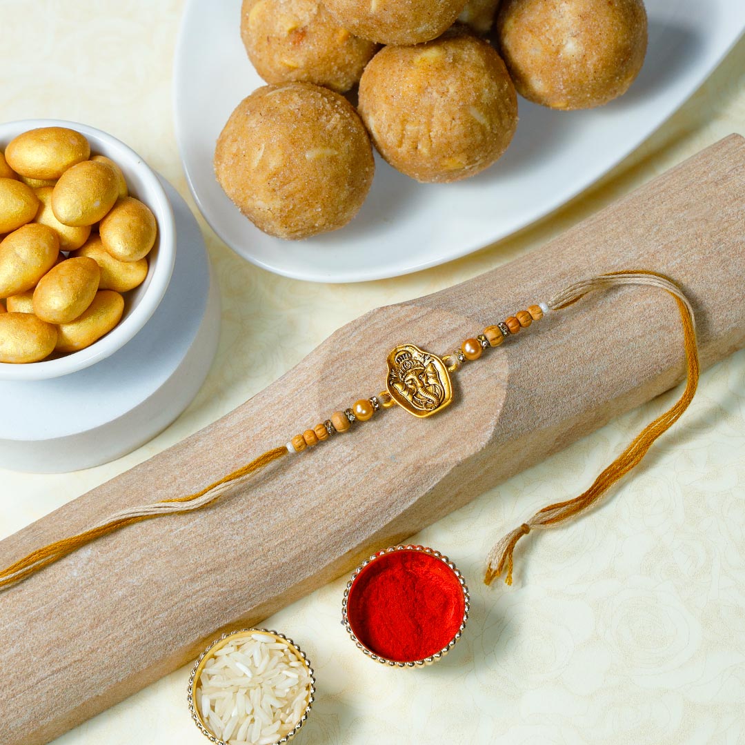 Send Golden Ganesh Rakhi With Panjiri Laddoo N Almond Dragees